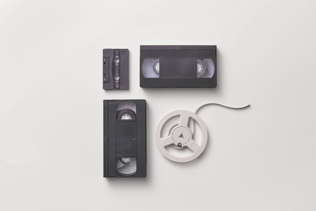 Videocassette, musicassetta e bobina su sfondo bianco